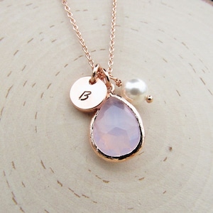 May include: A rose gold necklace with a pink teardrop-shaped gemstone pendant, a small pearl charm, and a personalized initial disc charm with the letter "B".