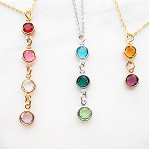 May include: Three gold necklaces with different colored gemstones. The necklaces have a single, double, and quadruple strand of gemstones. The gemstones are red, pink, clear, teal, green, orange, and purple.