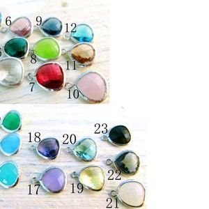 May include: Twenty-three teardrop-shaped glass pendants with silver settings. The pendants are in various colors, including red, green, blue, purple, pink, and clear.