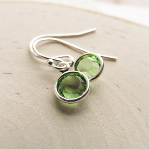 May include: A pair of silver earrings with green gemstone accents. The earrings have a simple, elegant design.