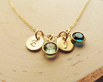 May include: Gold necklace with three charms: a round charm with the letter 'E' engraved on it, a round charm with the letter 'J' engraved on it, and a teal blue gemstone charm.
