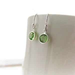 May include: A pair of silver dangle earrings with green gemstone accents.