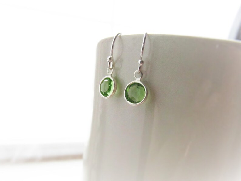 May include: A pair of silver dangle earrings with green gemstone accents.