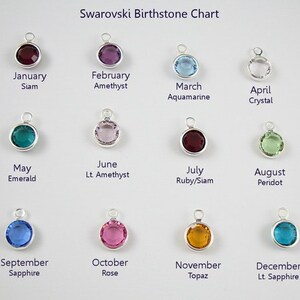 May include: A chart showing the Swarovski birthstones for each month of the year. The chart features a small, round, silver charm with a colored crystal for each month. The crystals are: January - Siam, February - Amethyst, March - Aquamarine, April - Crystal, May - Emerald, June - Light Amethyst, July - Ruby/Siam, August - Peridot, September - Sapphire, October - Rose, November - Topaz, December - Light Sapphire.