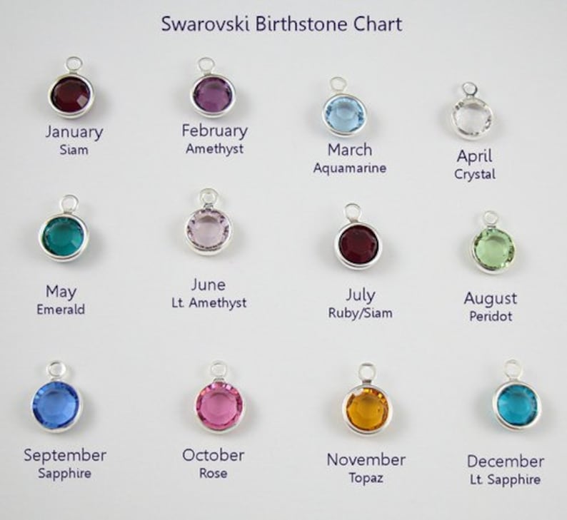 May include: A chart showing the Swarovski birthstones for each month of the year. The chart features a small, round, silver charm with a colored crystal for each month. The crystals are: January - Siam, February - Amethyst, March - Aquamarine, April - Crystal, May - Emerald, June - Light Amethyst, July - Ruby/Siam, August - Peridot, September - Sapphire, October - Rose, November - Topaz, December - Light Sapphire.