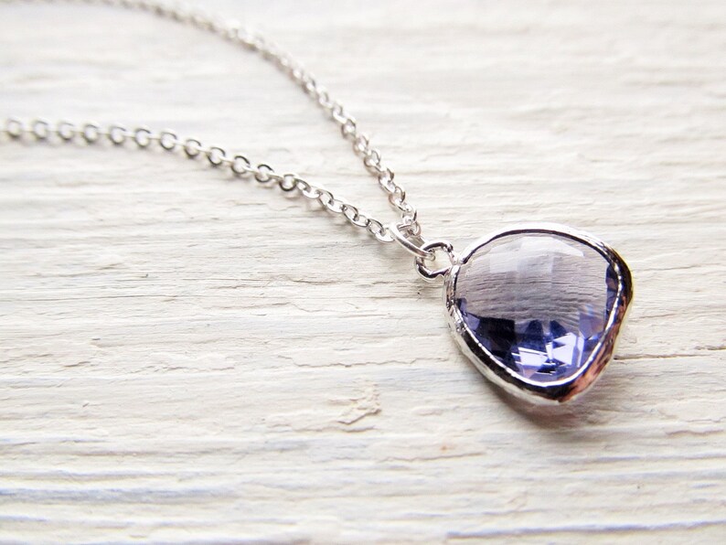 May include: A silver chain necklace with a large, faceted, light purple gemstone pendant.