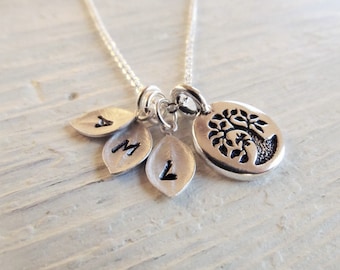 May include: Silver necklace with a tree charm and three leaf charms with the letters A, M, and L engraved on them.