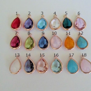 May include: Eighteen teardrop-shaped glass charms in various colors, including red, purple, blue, green, pink, orange, and turquoise. Each charm has a gold-toned bail.