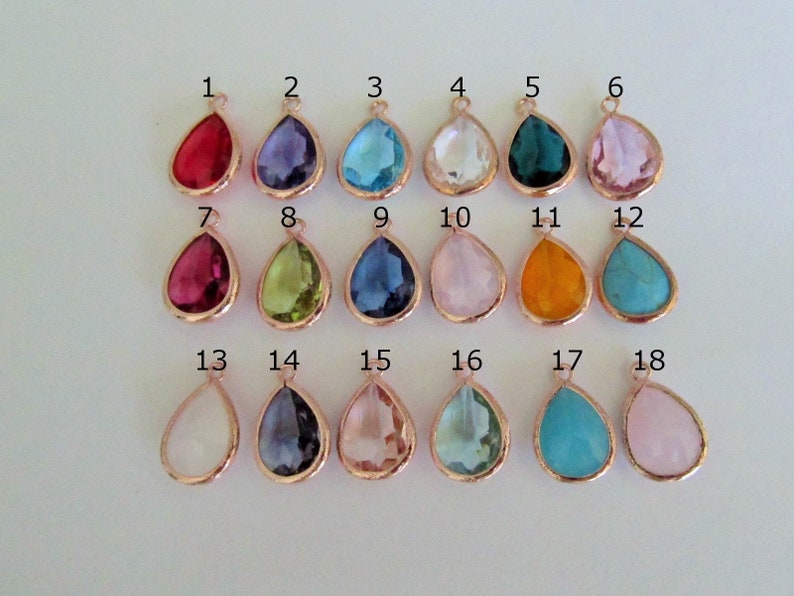 May include: Eighteen teardrop-shaped glass charms in various colors, including red, purple, blue, green, pink, orange, and turquoise. Each charm has a gold-toned bail.