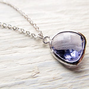 May include: A silver chain necklace with a light purple gemstone pendant. The pendant is shaped like a teardrop and has a faceted design.