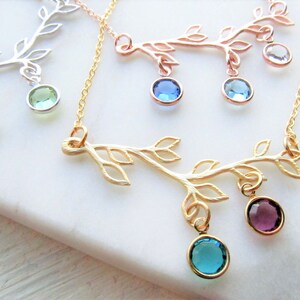 May include: Three gold, silver, and rose gold necklaces with a delicate branch design and dangling gemstone charms. The charms are in shades of blue, green, and purple.