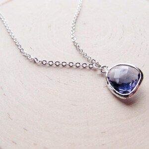 May include: A silver chain necklace with a pendant featuring a faceted, clear purple gemstone.