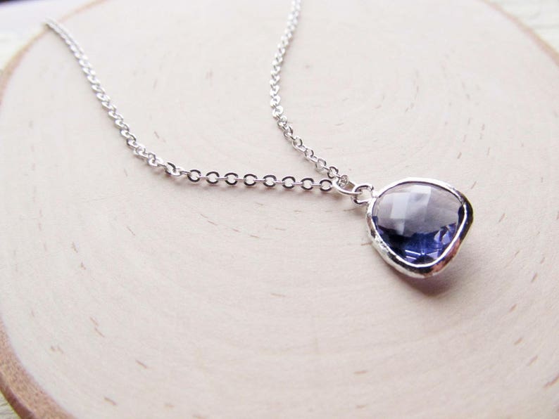 May include: A silver chain necklace with a pendant featuring a faceted, clear purple gemstone.