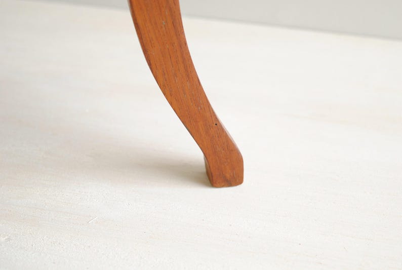 K&ouml;nnte beinhalten: Ein gebogenes Holzm&ouml;belbein, wahrscheinlich von einem Stuhl oder Tisch, wird vor einem wei&szlig;en Hintergrund dargestellt. Das Bein hat eine warme, mittelbraune Farbe mit einer glatten, polierten Oberfl&auml;che. Das Design ist klassisch und elegant.