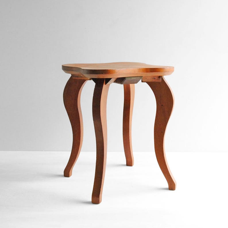 K&ouml;nnte beinhalten: Kleiner Beistelltisch aus Holz im antiken Stil mit einem einzigartigen, geschwungenen Design. Der Tisch hat eine hellbraune Tischplatte und vier elegant geschwungene Beine. Die Beine sind rotbraun und verleihen dem Tisch einen Hauch von Vintage-Charme. Ideal f&uuml;r Wohn- oder Schlafzimmer.
