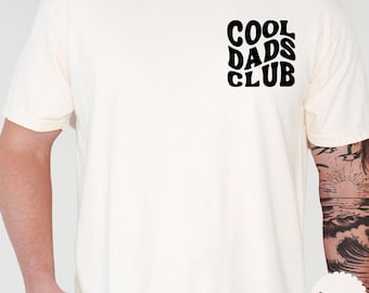 May include: A white t-shirt with the text "COOL DADS CLUB" in black retro-style lettering.