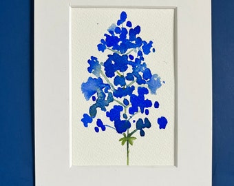 May include: A watercolor painting of a blue flower with a white background. The flower is in a simple frame.