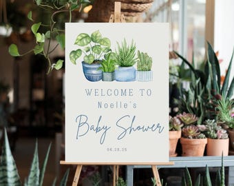 May include: Welcome to Noelle's Baby Shower sign with a watercolor illustration of potted plants in blue and green hues. The date 06.28.25 is printed below the text.