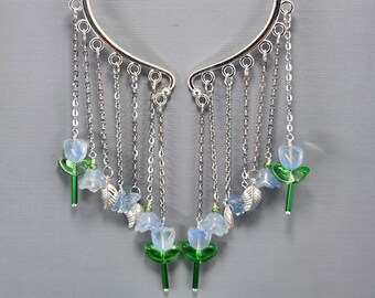 May include: Silver ear cuff with multiple chains and blue flower charms. The chains are connected to the ear cuff and dangle down with blue flower charms at the end of each chain.