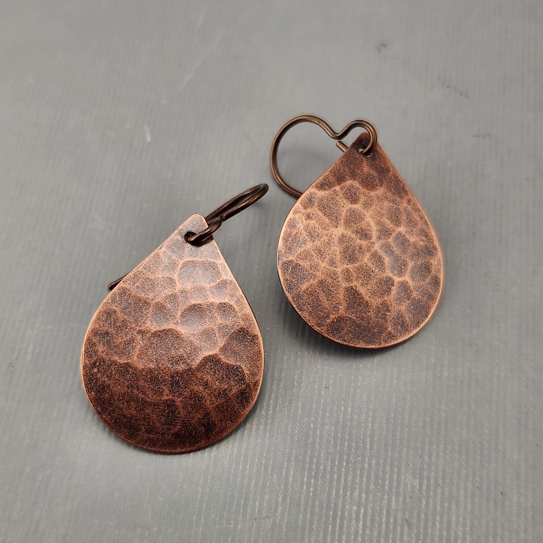 May include: A pair of copper teardrop earrings with a hammered texture.