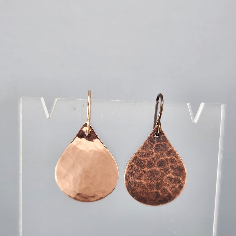 May include: A pair of hammered copper teardrop earrings with a gold and silver finish.