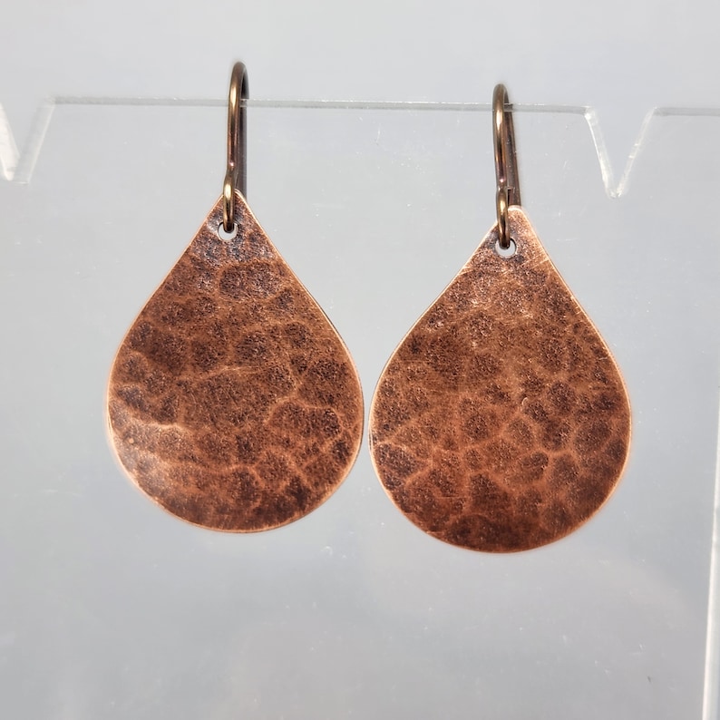 May include: A pair of hammered copper teardrop earrings with a rustic finish.