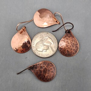May include: Three pairs of hammered copper teardrop earrings with a hammered texture. The earrings are approximately the size of a US quarter.
