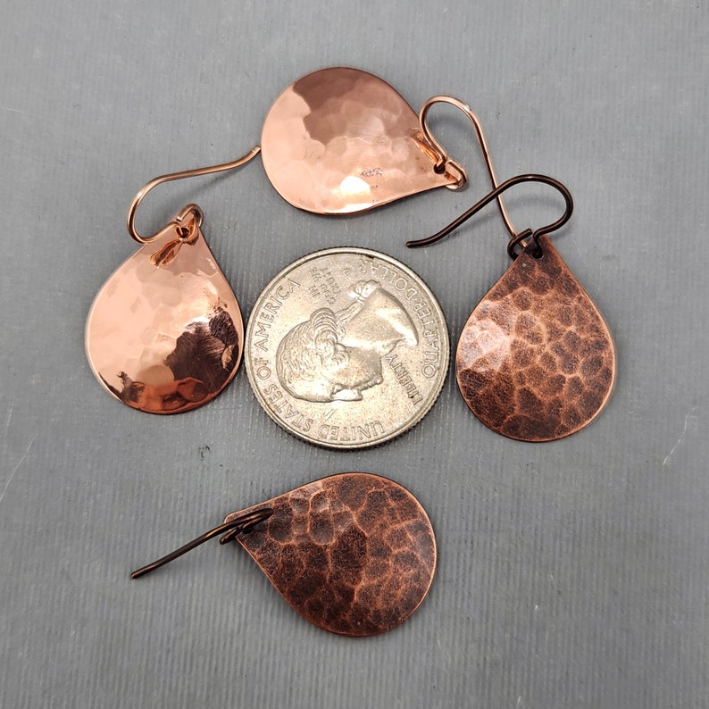 May include: Three pairs of hammered copper teardrop earrings with a hammered texture. The earrings are approximately the size of a US quarter.