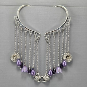 May include: Silver ear cuff with dangling chains and purple beads. The chains have small teacup charms and teapot charms at the ends.