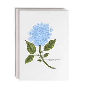 May include: A white greeting card featuring a blue hydrangea illustration with green leaves and the text "...with God all things are possible." Matthew 19:26 printed in small black font near the stem of the flower on the front of the card.