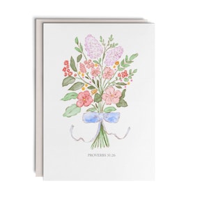 May include: A white greeting card featuring a watercolor illustration of a floral bouquet with pink, purple, and green tones, tied with a light blue ribbon. The text PROVERBS 31:26 is printed in black at the bottom center of the card design.