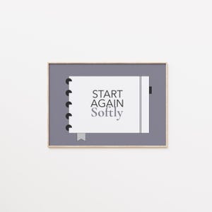 Può includere: Stampa incorniciata con un design a quaderno. Il testo recita "START AGAIN Softly" in nero e grigio. Il quaderno è ambientato su uno sfondo grigio, all'interno di una cornice di legno.