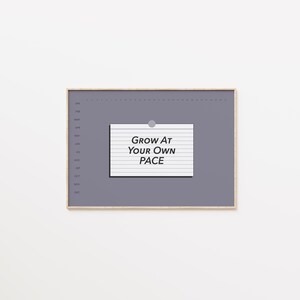 Può includere: Una lavagna grigia rettangolare con cornice in legno. Un blocco note bianco con il testo "Grow At Your Own Pace" è attaccato con un magnete argentato. La lavagna ha un layout del calendario sul lato sinistro.