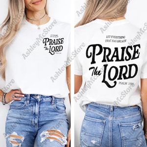 May include: White t-shirt with the text "PRAISE THE LORD" in black, with "Psalm 150:6" below. The front of the shirt has the same text, with "LET EVERYTHING THAT HAS BREATH" above. The shirt is paired with blue jeans.