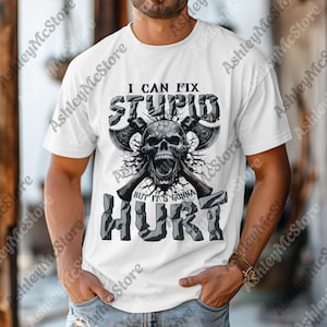 May include: White t-shirt featuring a skull graphic with crossed axes and the text "I CAN FIX STUPID BUT IT'S GONNA HURT" in a distressed, gray font. The design has a grunge aesthetic.