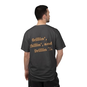 May include: Dark gray t-shirt with the words "Grillin', Chillin', and Drillin'" printed in a light brown color. The shirt has a crew neck and short sleeves. The text is centered on the back of the shirt.
