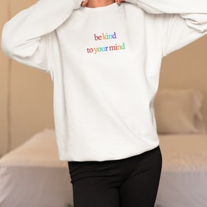 Puede incluir: Sudadera blanca con el texto "be kind to your mind" en colores arcoíris.