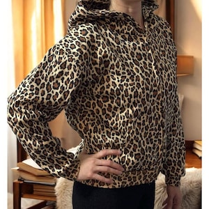 Puede incluir: Una sudadera con capucha de color marrón y negro con estampado de leopardo.