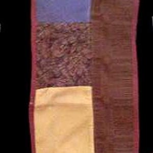 May include: A rectangular patchwork table runner featuring a variety of fabric squares in solid colors including purple, yellow, red, and black, alongside patterned sections with floral, star, and abstract designs, all bordered by a thin red trim.