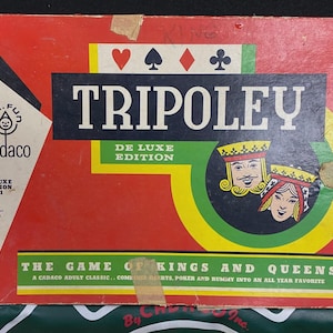 May include: A vintage Tripoley De Luxe Edition game box. The box is red with a black and white design, featuring the game title and card suit symbols. The box also includes the text "The Game of Kings and Queens".