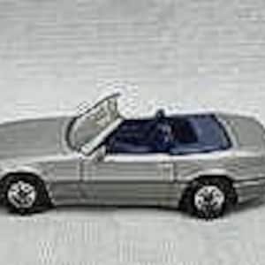 May include: A silver convertible toy car with a blue interior and open top. The car has black wheels and is set against a light background. The car's design includes detailed features.