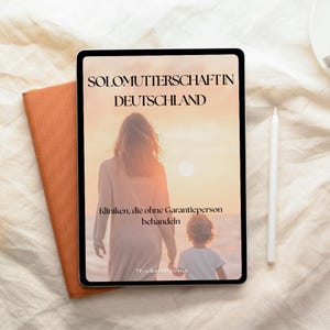 May include: A digital tablet displaying the text "SOLOMUTTERSCHAFT IN DEUTSCHLAND" with an image of a mother and child on a beach. A white stylus and an orange book are next to the tablet. The image has a warm, sunset color scheme.