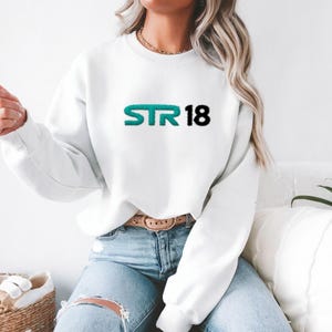 May include: White sweatshirt with a teal green and black graphic that says "STR18".