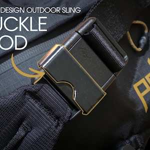 May include: Close-up of a black adjustable buckle on a black sling bag. The buckle has a gold trim and the bag has a gold "PD" logo.