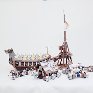 May include: A set of wooden model war machines, including a Viking longship with a dragon figurehead, a trebuchet, and siege engines. The models are brown, silver, and blue, with detailed construction.