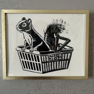May include: A black and white illustration of a squirrel sitting in a market basket. The basket is labeled "Market Basket".