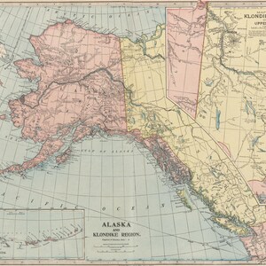 以下が含まれることがあります： 「Alaska and Klondike Region」と題されたヴィンテージスタイルの地図。緯度と経度のグリッド線が描かれています。地図はくすんだピンク、黄色、青の色調で地域を区分けしており、挿入枠にはアリューシャン列島が示されています。