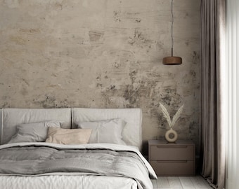 May include: A white bed with a gray duvet and a beige throw pillow. The bed is in a bedroom with a concrete wall, a brown nightstand, and a brown pendant light hanging from the ceiling.