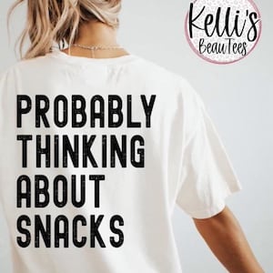 Pode incluir: Camiseta branca com texto preto que diz "Probably Thinking About Snacks".