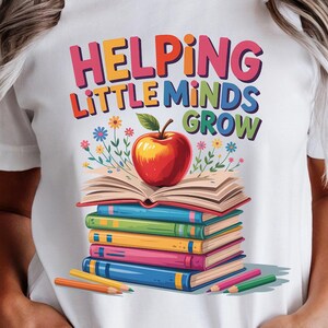 May include: White t-shirt with the text "Helping Little Minds Grow" in colorful letters. The graphic features a stack of books, a red apple, and pencils. The design is perfect for teachers or anyone who loves education.